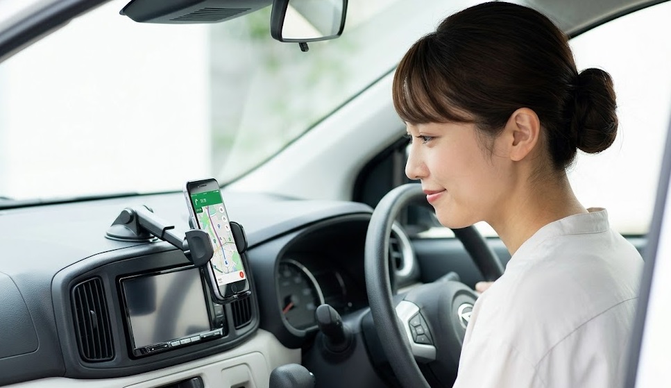 ミライースの車内で、高額な純正ナビの代わりにスマートフォンのナビアプリを活用する日本人女性。賢いオプション選び。
